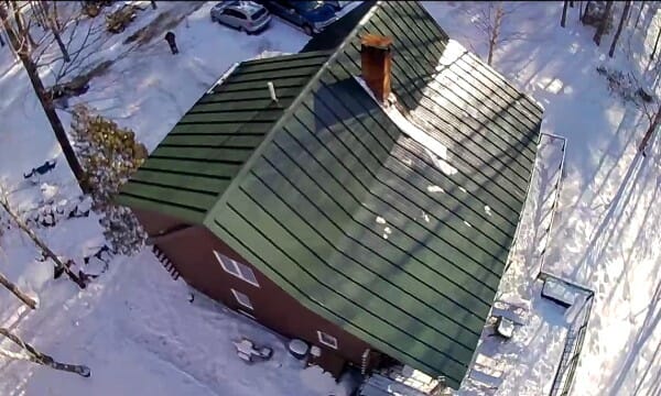 Green metal roof on home surrounded by snow